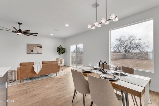 dining area with light wood-type flooring and ceiling fan with notable chandelier