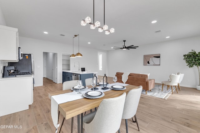 dining space featuring light hardwood / wood-style flooring and ceiling fan with notable chandelier