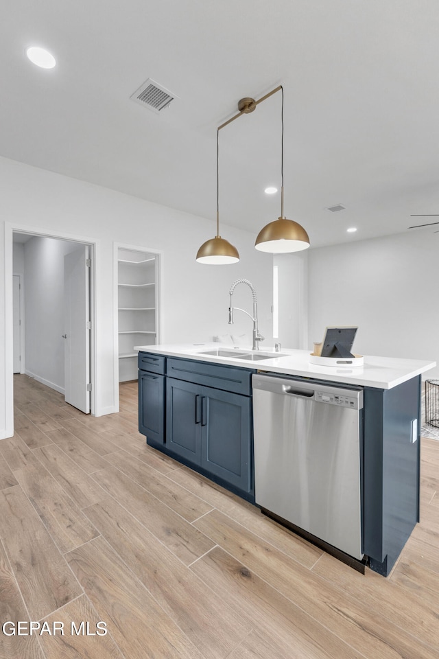 kitchen with a kitchen island with sink, sink, light hardwood / wood-style flooring, stainless steel dishwasher, and pendant lighting