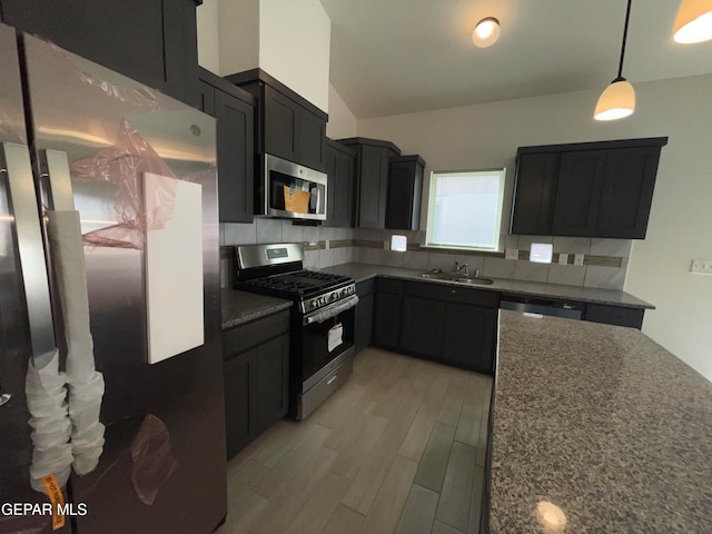 kitchen with sink, stainless steel appliances, tasteful backsplash, and dark stone counters