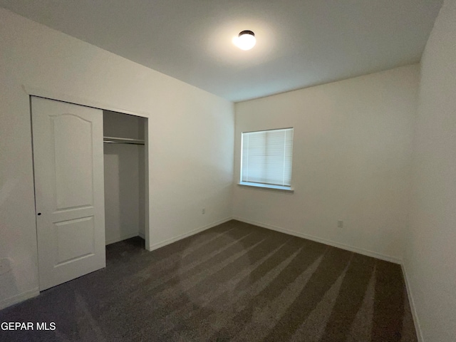 unfurnished bedroom with a closet and dark carpet