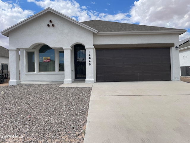 single story home with central AC unit and a garage