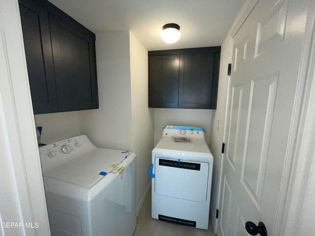 clothes washing area with washer and dryer, light tile floors, and cabinets