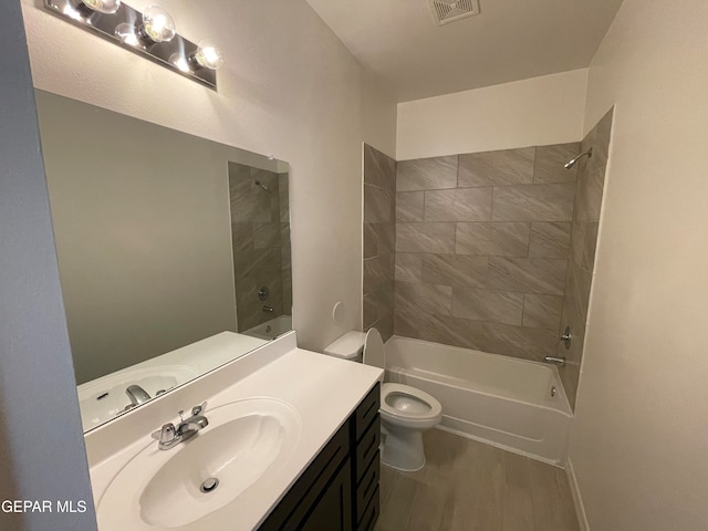 full bathroom with vanity, tiled shower / bath combo, wood-type flooring, and toilet