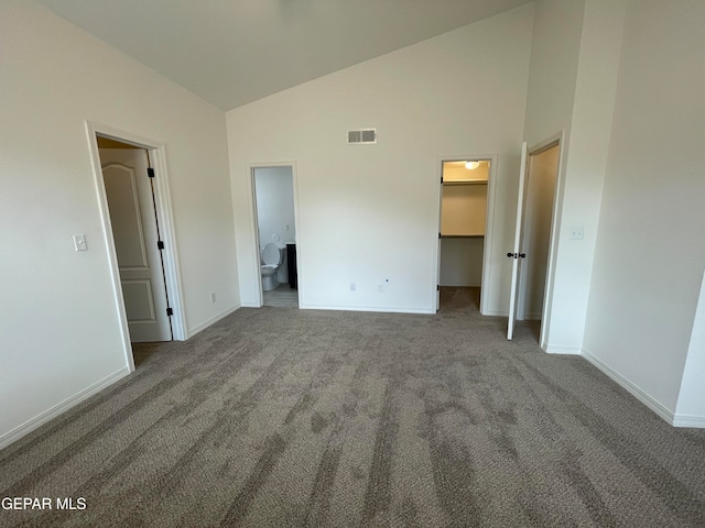 unfurnished room with dark colored carpet and high vaulted ceiling