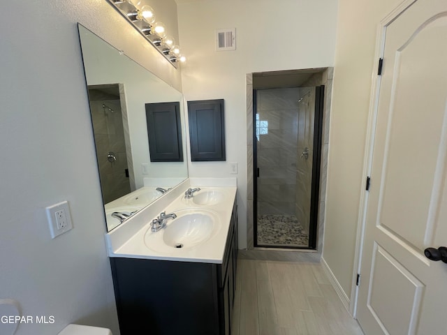 bathroom with double sink, an enclosed shower, and vanity with extensive cabinet space