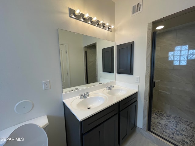 bathroom featuring toilet, large vanity, walk in shower, and dual sinks