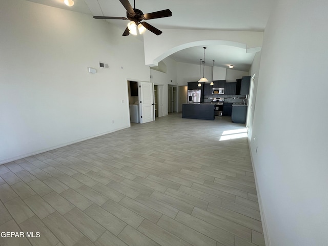 unfurnished living room featuring high vaulted ceiling, light hardwood / wood-style flooring, and ceiling fan