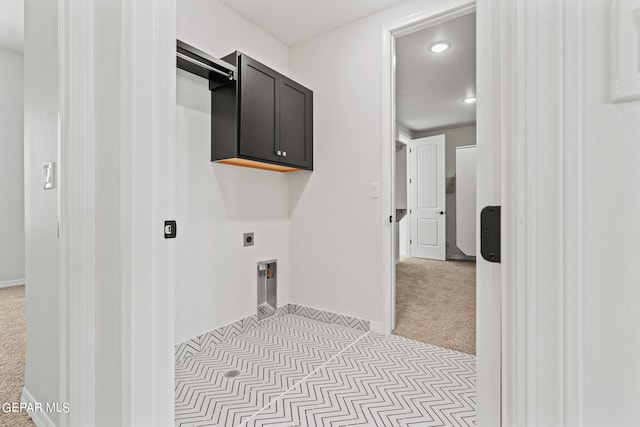 washroom featuring light carpet, electric dryer hookup, and cabinets