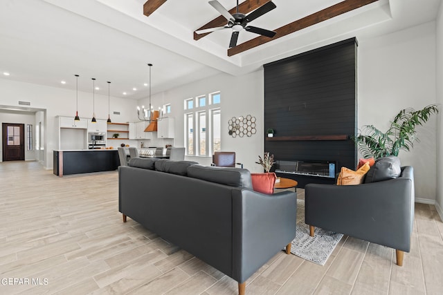 living room featuring light hardwood / wood-style flooring, a fireplace, and ceiling fan with notable chandelier