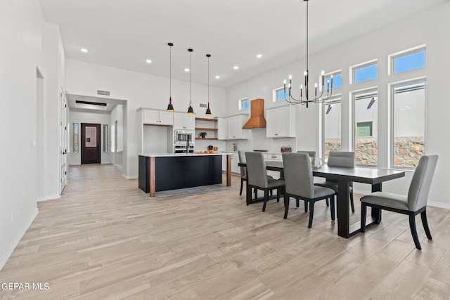 dining space featuring an inviting chandelier, light wood-type flooring, and a high ceiling