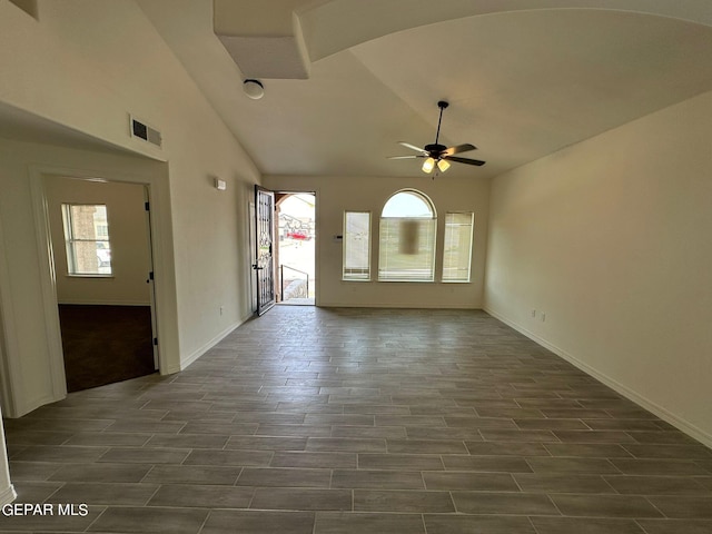 unfurnished living room featuring dark tile patterned flooring, a wealth of natural light, ceiling fan, and vaulted ceiling