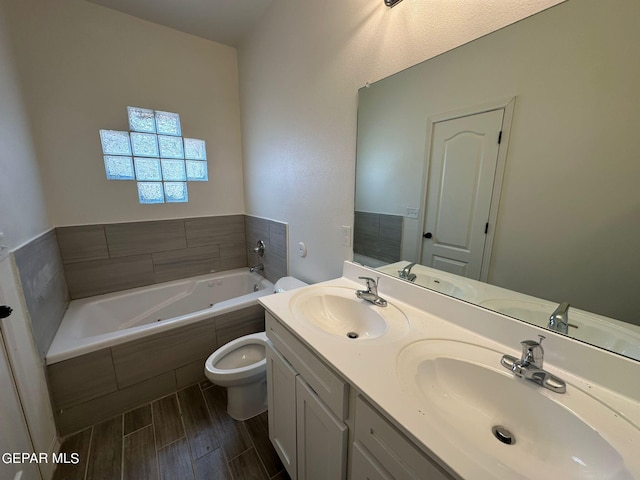 bathroom with a relaxing tiled tub, dual vanity, and toilet