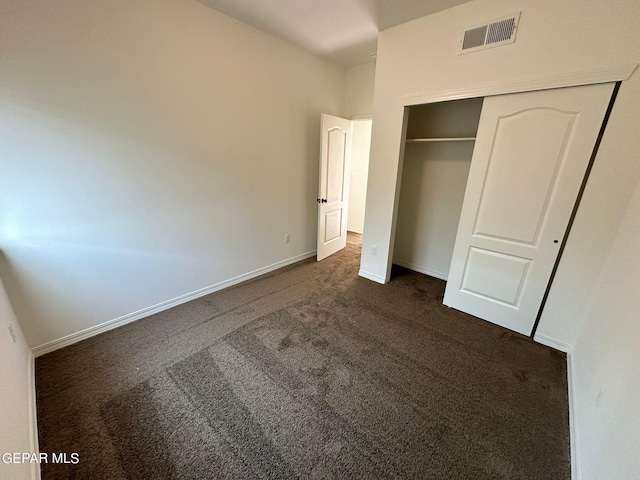 unfurnished bedroom featuring dark carpet and a closet