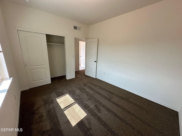 unfurnished bedroom with a closet and dark carpet