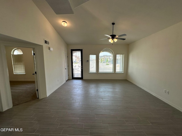 spare room featuring vaulted ceiling, dark colored carpet, and ceiling fan