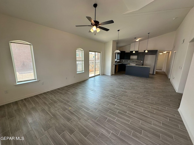 unfurnished living room featuring a wealth of natural light, lofted ceiling, ceiling fan, and dark hardwood / wood-style floors