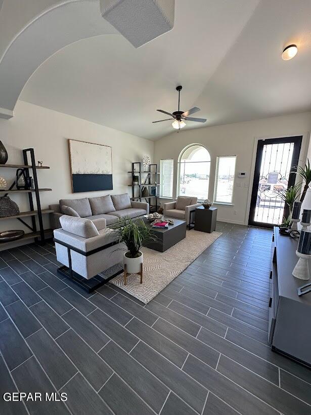 living room featuring dark wood-type flooring, ceiling fan, and vaulted ceiling