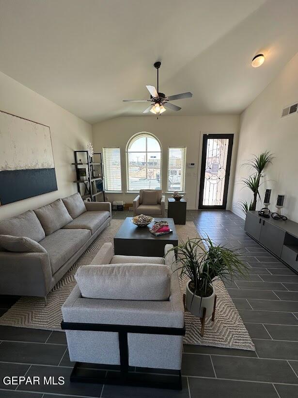 living room with ceiling fan, lofted ceiling, and dark tile floors