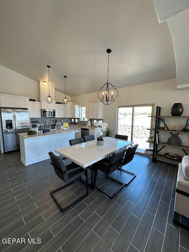 dining room featuring an inviting chandelier, dark wood-type flooring, and vaulted ceiling