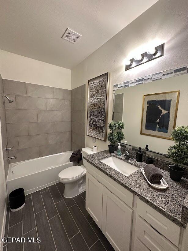 full bathroom with tiled shower / bath, toilet, and vanity