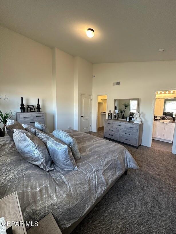 bedroom with high vaulted ceiling, a walk in closet, and dark colored carpet