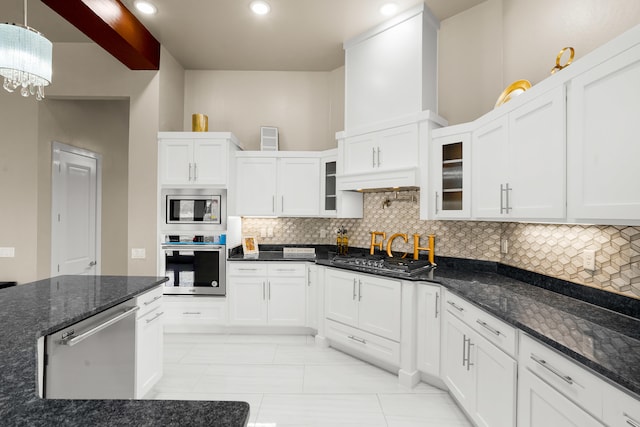 kitchen featuring dark stone countertops, light tile floors, appliances with stainless steel finishes, and an inviting chandelier