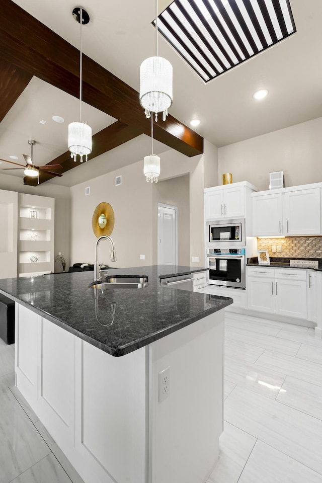 kitchen with sink, appliances with stainless steel finishes, a center island with sink, decorative light fixtures, and white cabinetry