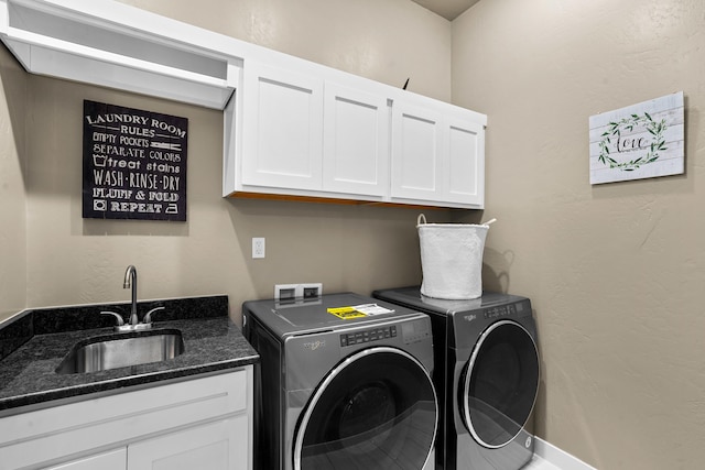 clothes washing area with washer and clothes dryer, cabinets, and sink