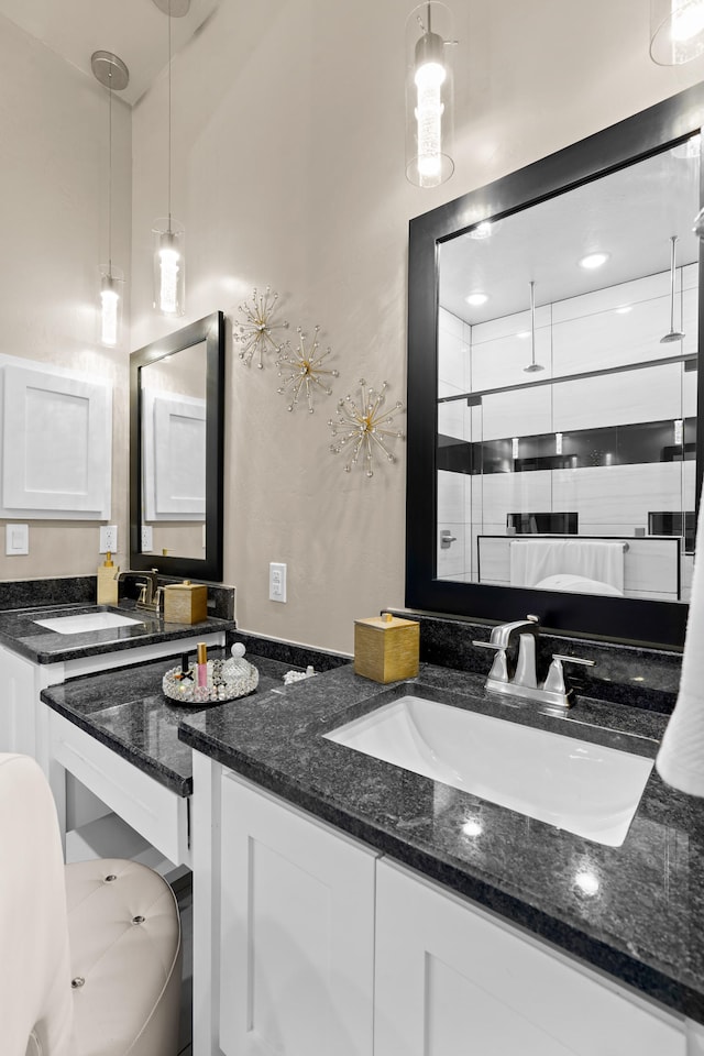 kitchen featuring dark stone counters, white cabinets, decorative light fixtures, and sink