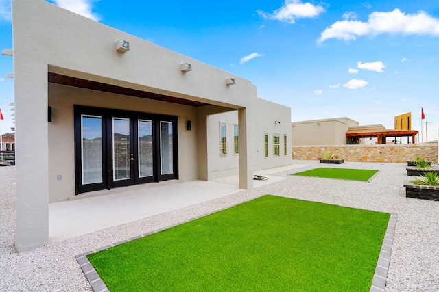 rear view of property featuring french doors, a lawn, and a patio area