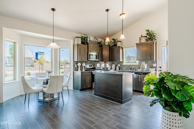 kitchen featuring appliances with stainless steel finishes, a kitchen island, hanging light fixtures, tasteful backsplash, and dark hardwood / wood-style flooring