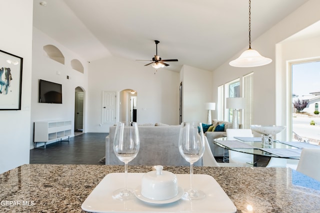 kitchen featuring pendant lighting, light stone countertops, dark hardwood / wood-style floors, ceiling fan, and lofted ceiling