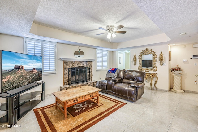 living room featuring light tile patterned floors, a stone fireplace, a textured ceiling, and ceiling fan