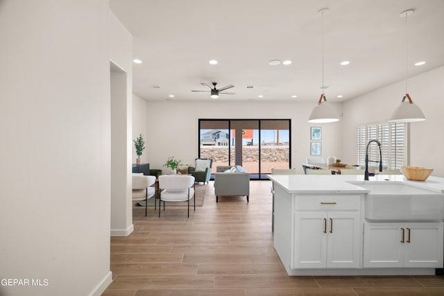 kitchen with a wealth of natural light, ceiling fan, sink, decorative light fixtures, and white cabinets