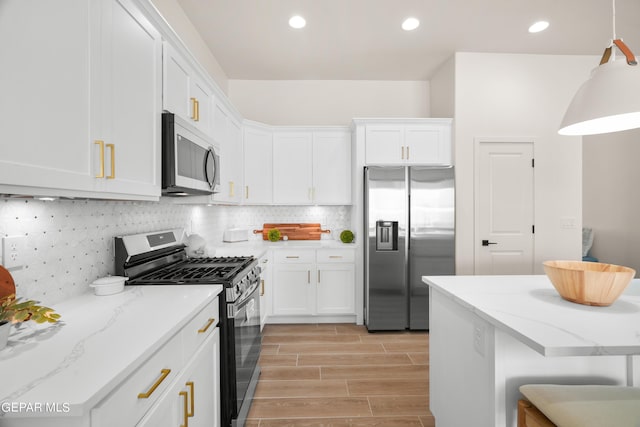 kitchen with a kitchen bar, backsplash, stainless steel appliances, decorative light fixtures, and white cabinets