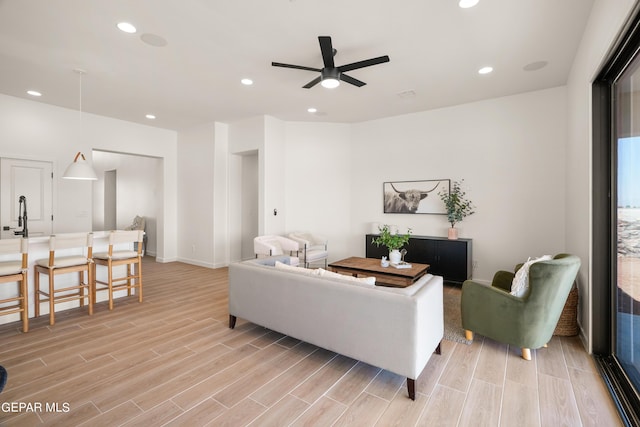 living room featuring ceiling fan, sink, and light hardwood / wood-style flooring