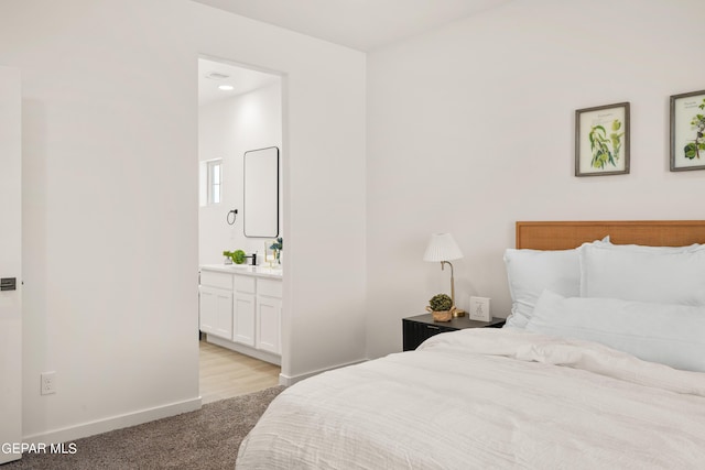 bedroom featuring light colored carpet and ensuite bath