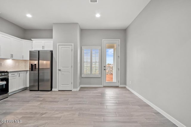 kitchen featuring tasteful backsplash, white cabinetry, stainless steel appliances, and light hardwood / wood-style floors