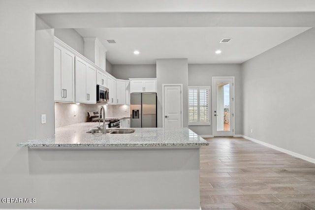 kitchen featuring sink, white cabinetry, light hardwood / wood-style floors, kitchen peninsula, and stainless steel appliances