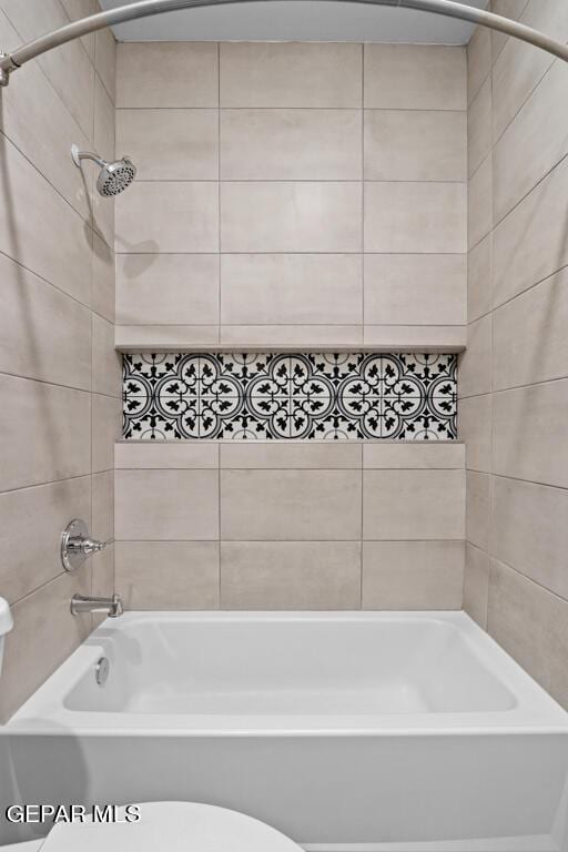 bathroom with tiled shower / bath combo and toilet