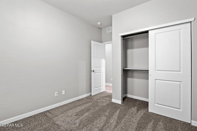 unfurnished bedroom with dark colored carpet and a closet