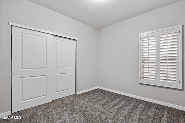 unfurnished bedroom featuring dark carpet and a closet