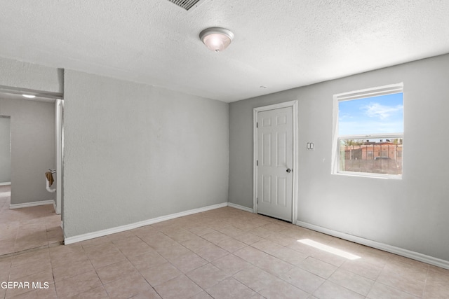 tiled spare room with a textured ceiling