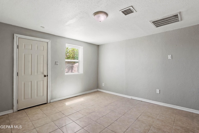 unfurnished room featuring light tile flooring and a textured ceiling