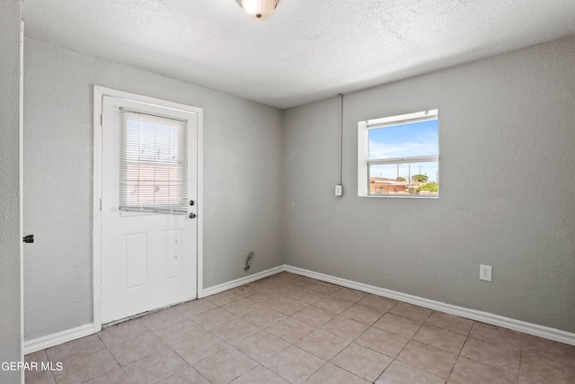 interior space with light tile floors, a textured ceiling, and a wealth of natural light