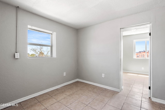 unfurnished room featuring light tile floors, plenty of natural light, and a textured ceiling