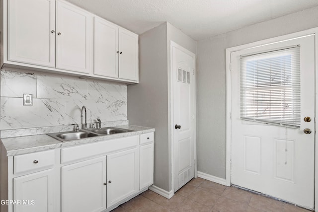 kitchen with white cabinets, sink, light tile floors, and tasteful backsplash