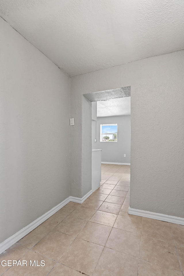 empty room featuring light tile floors and a textured ceiling