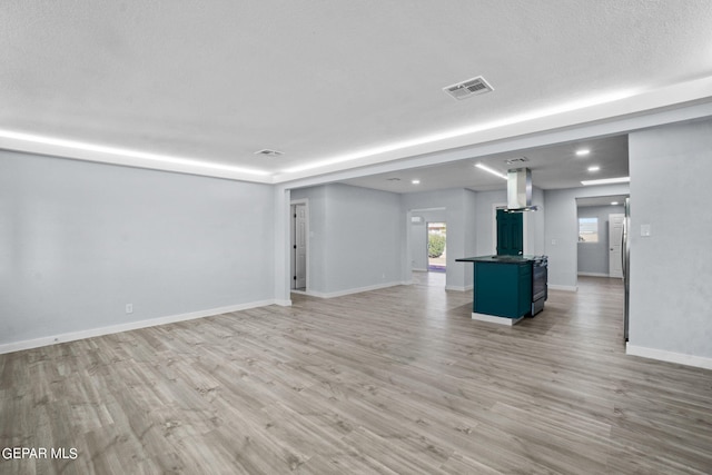 unfurnished living room featuring a textured ceiling and light hardwood / wood-style floors